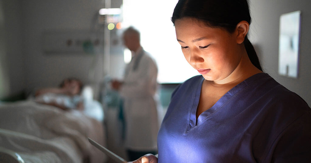 Nurse looking at a tablet in a patient's room