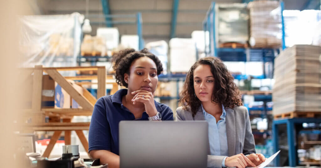 coworkers in a factory reviewing work on a computer