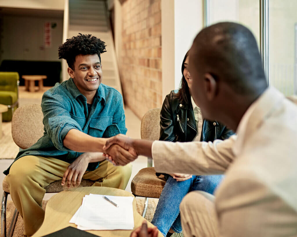 A couple shaking hands with a businessman after signing commercial loan documents