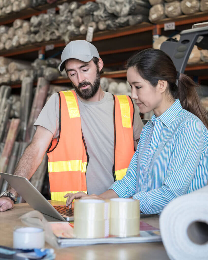 Two manufacturing coworkers together looking at a laptop