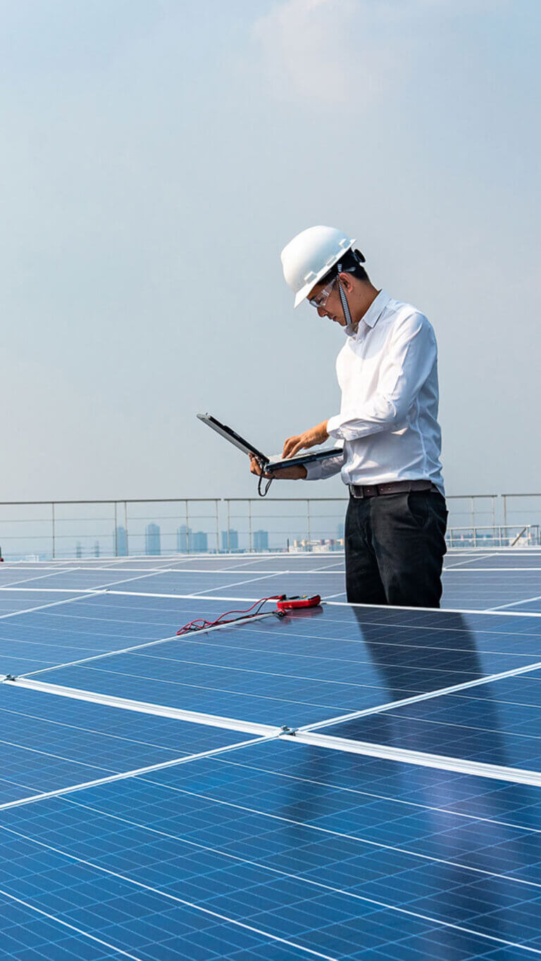 Male worker on laptop while looking at solar panels
