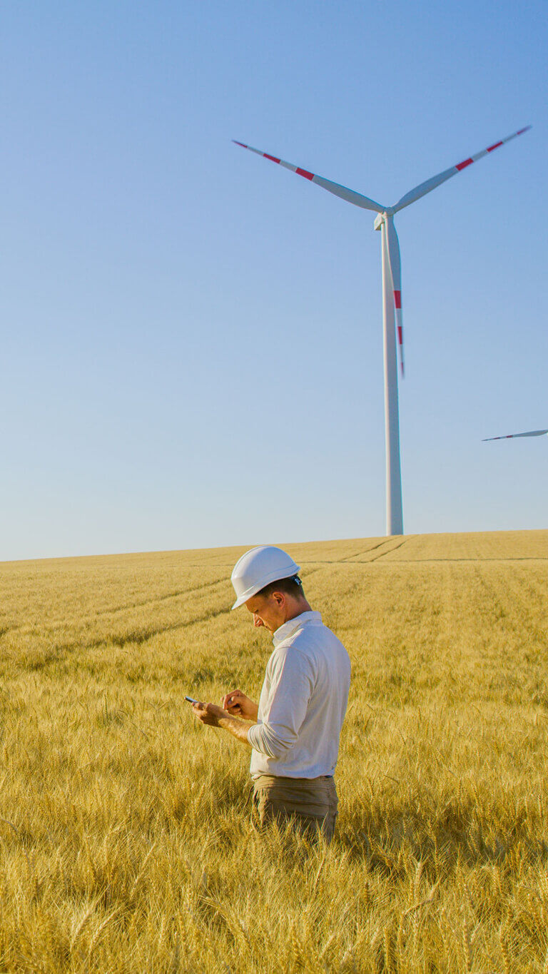 Electrical engineer next to windmills provided by renewable energy loans