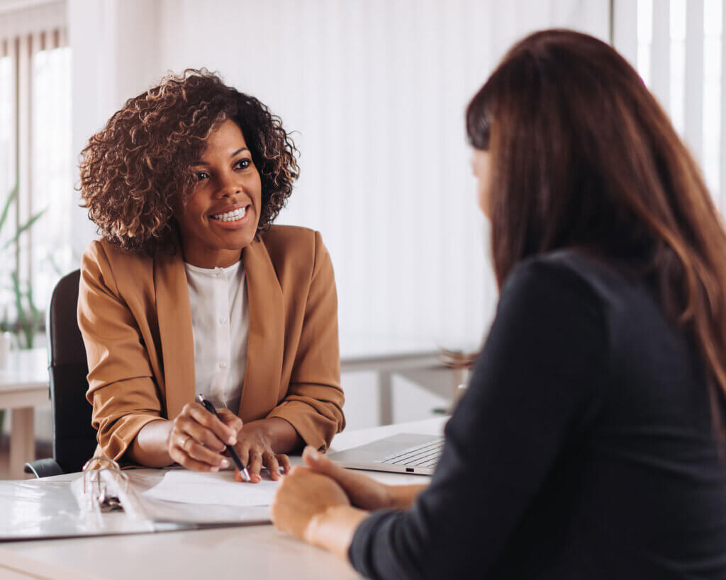 Smiling female financial consultant manager talking with a female client at a bank.