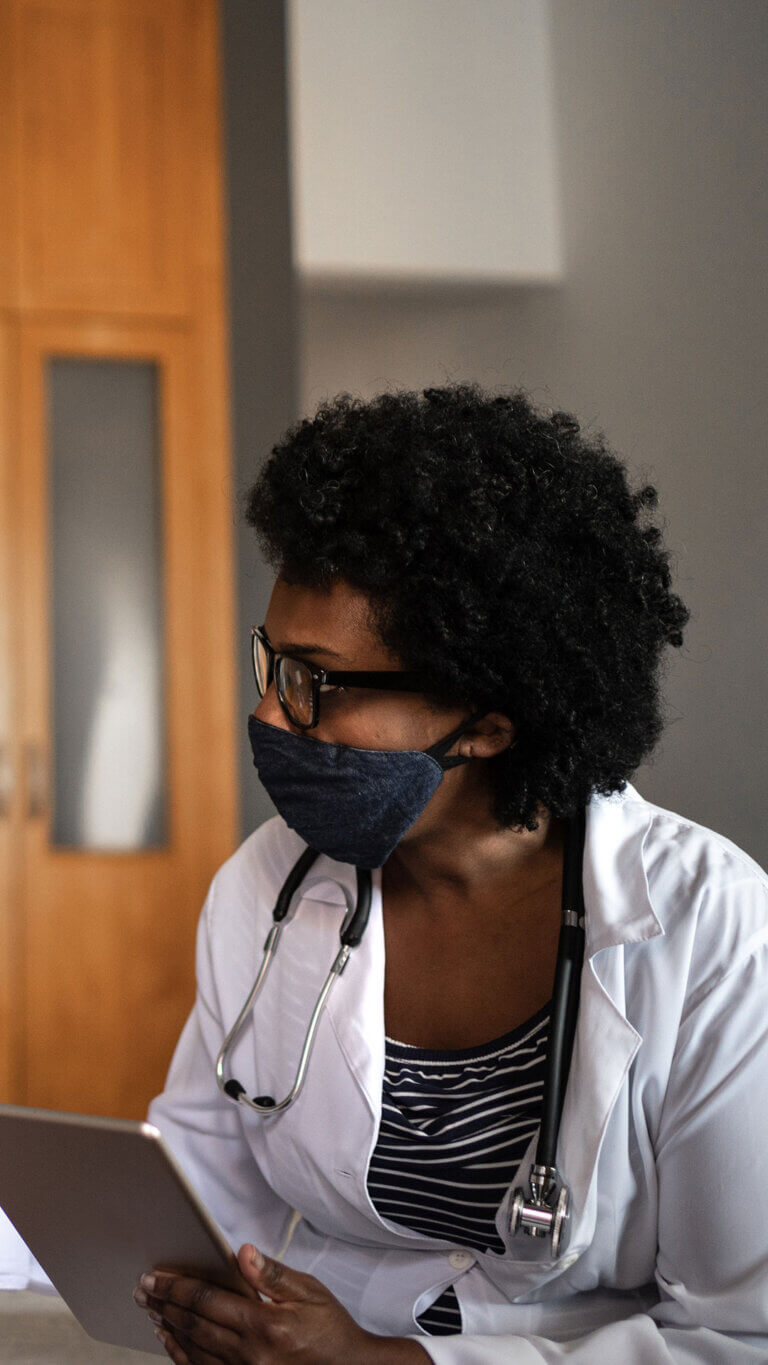 A female healthcare worker is busy on her tablet, sitting at a table.
