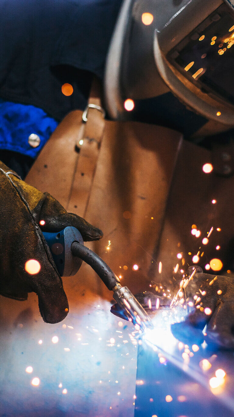 industrial welder with torch in manufacturing plant that received manufacturing loans