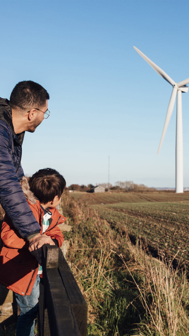 Father and son looking at their neighbor's renewable energy wind farm.