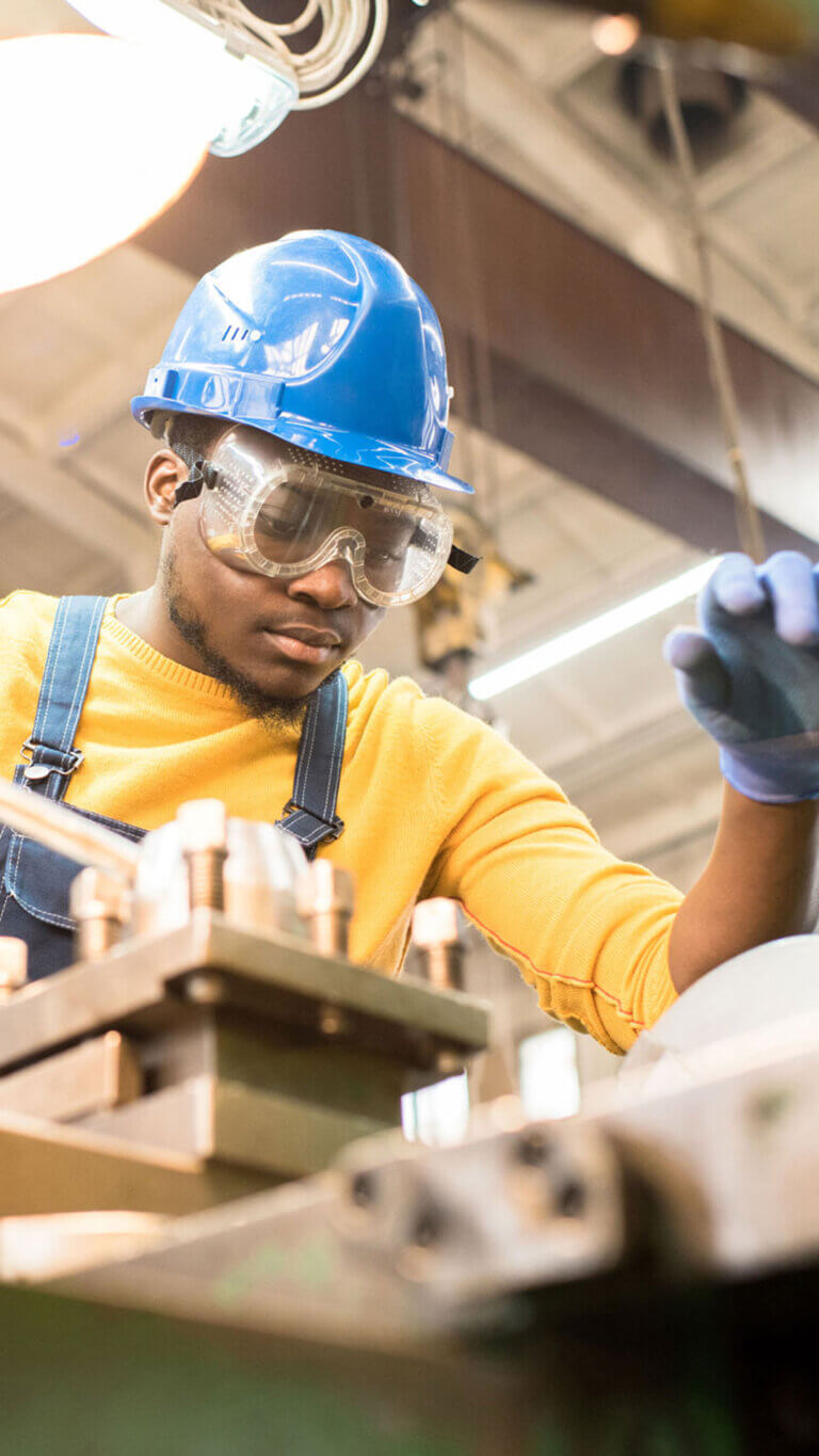 Factory worker wearing safety gear inspecting his work.