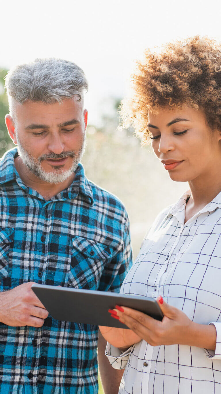 A farmer and his loan representative going over terms on her tablet.