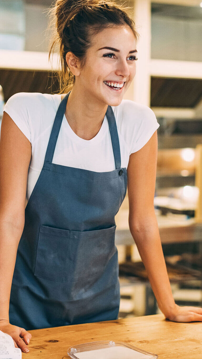 SBA bakery shop owner standing at counter interacting with customers.