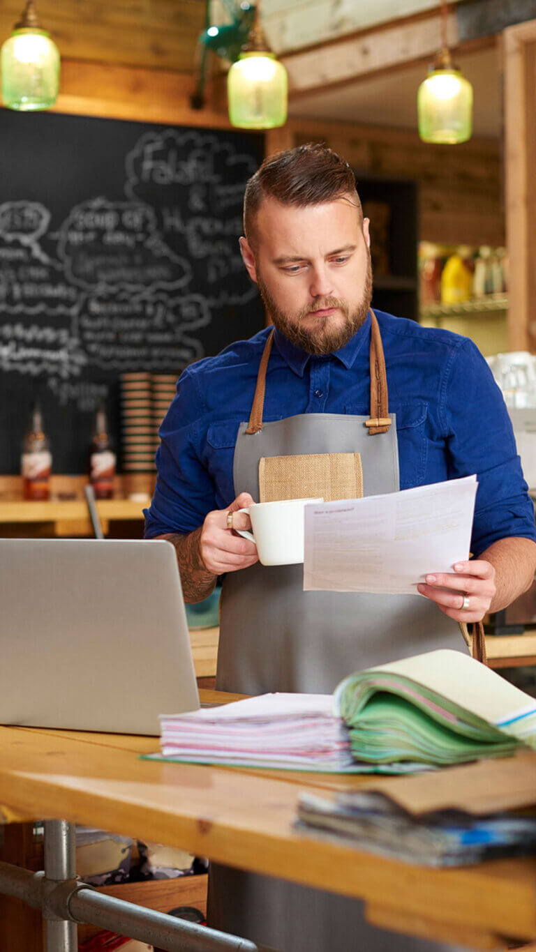 Small business coffee shop owner reviewing SBA loan paperwork.