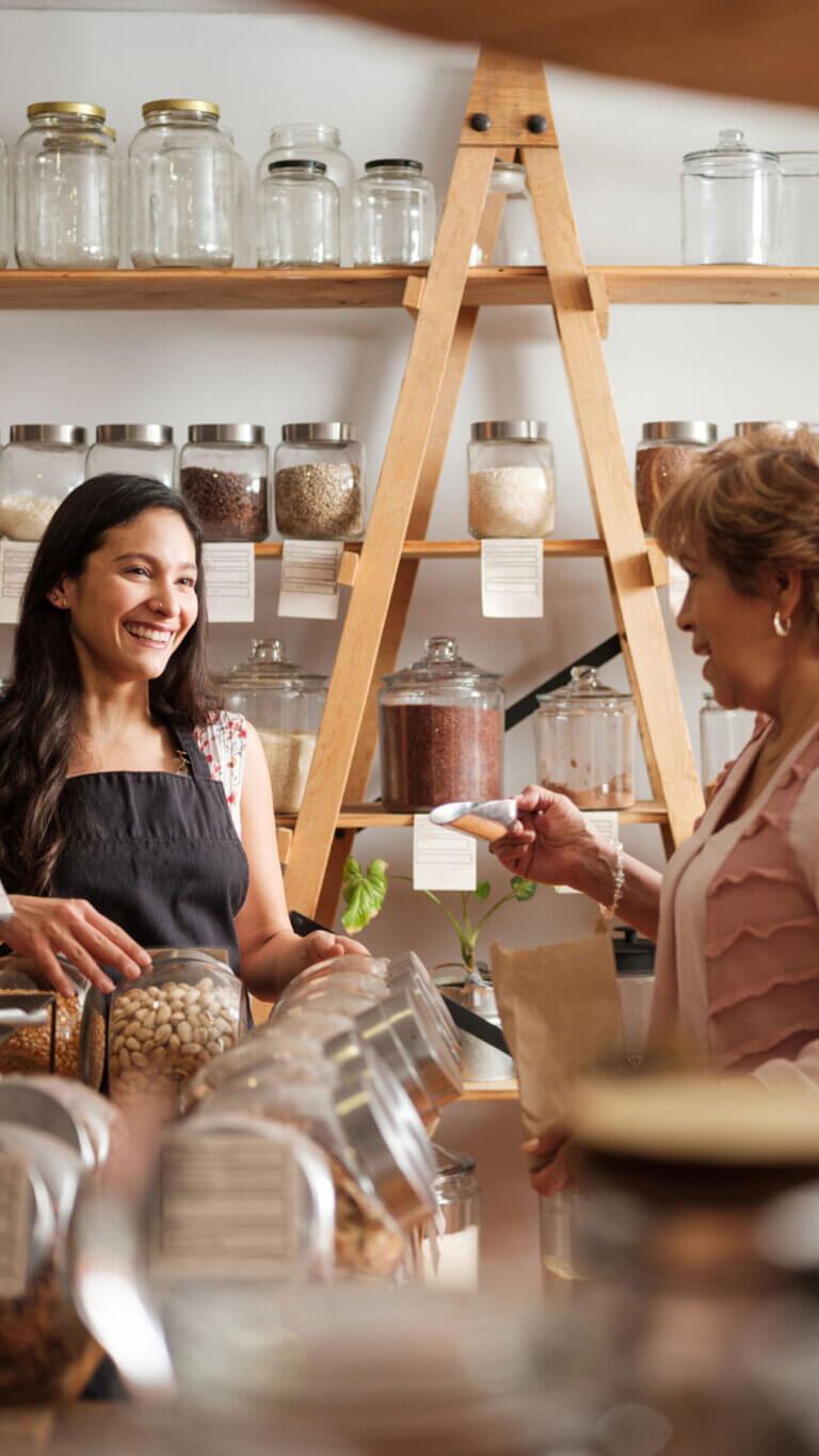 Small business owner standing with customer selecting grains for her purchase.