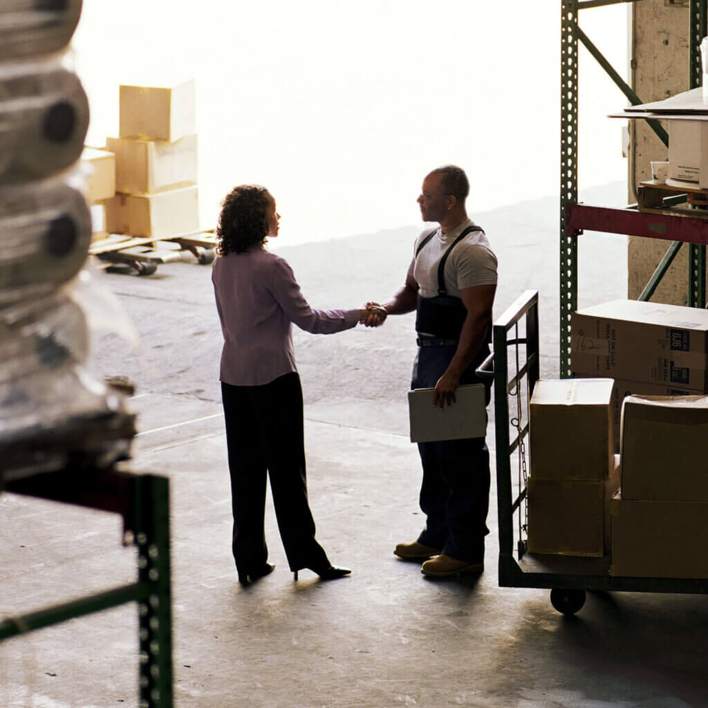 Two people shaking hands while discussing manufacturing loans