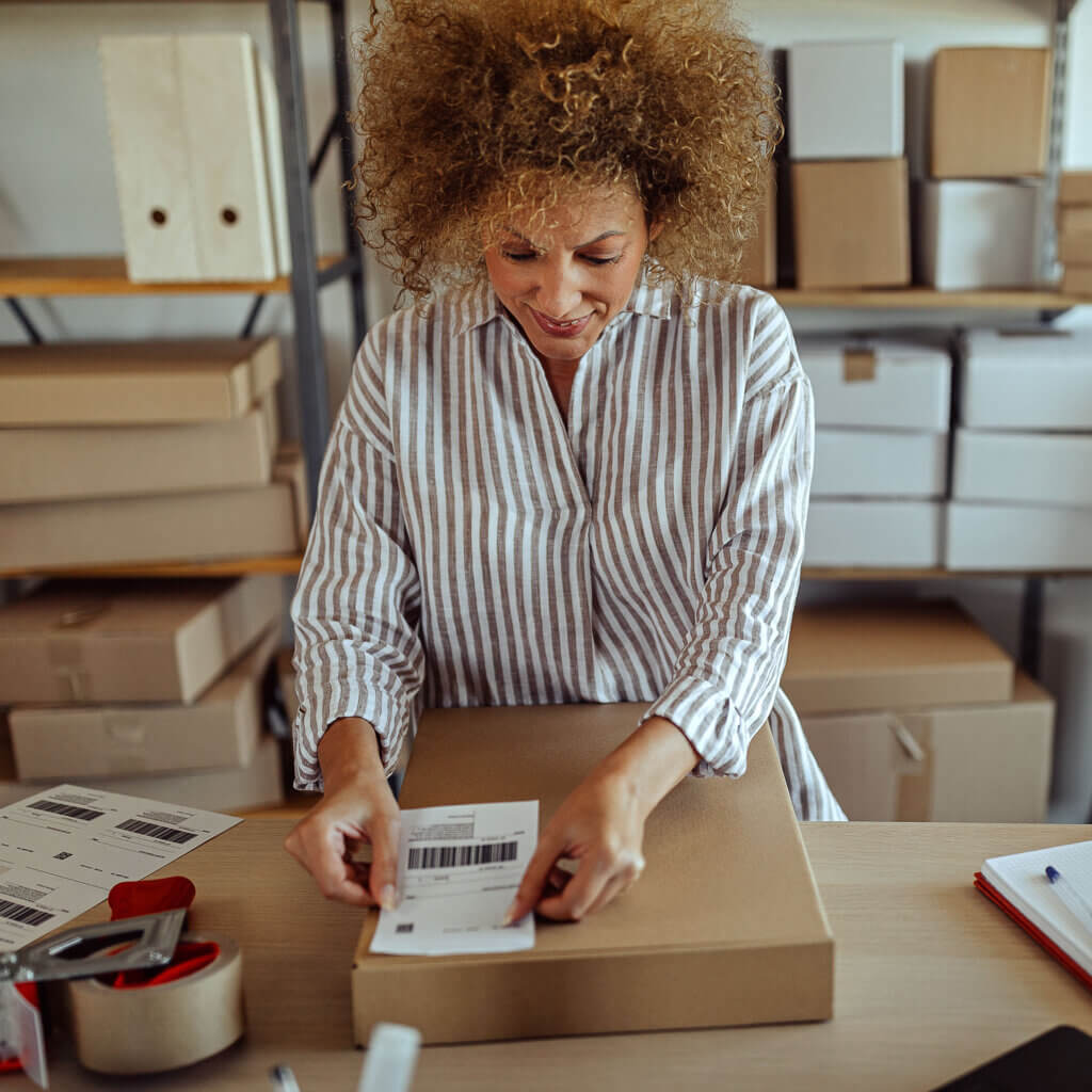 Small business owner putting shipping label on brown cardboard box