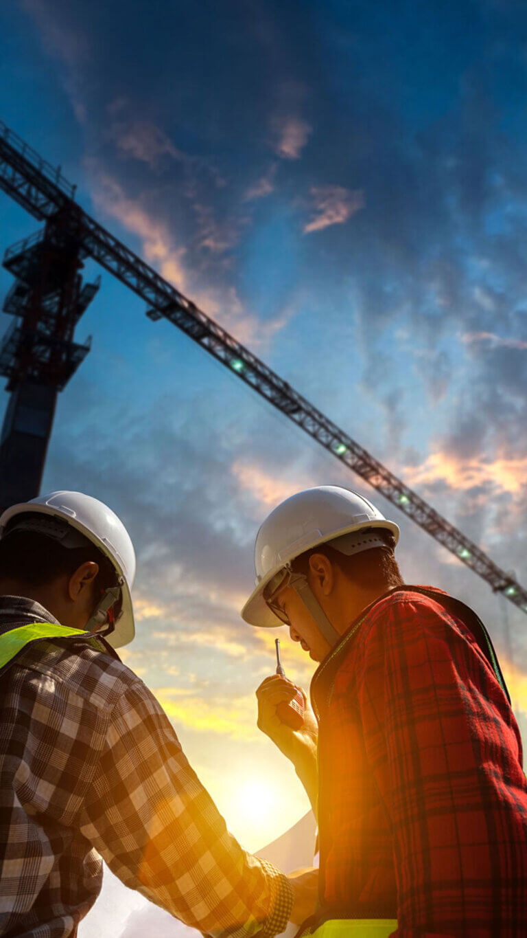 Two construction workers reviewing plans on site.