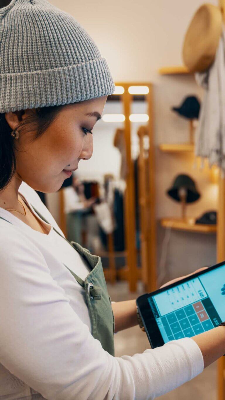 Small business manager running credit card on tablet in shop