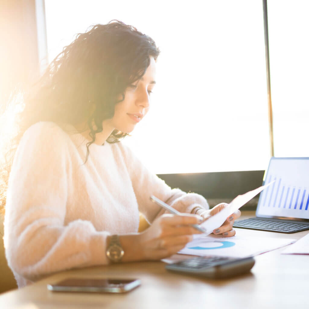 Woman working at a desk with tablet and papers