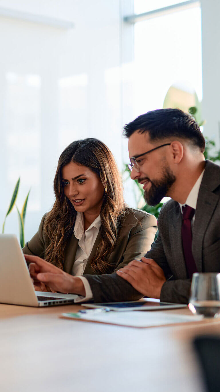 Two business loan origination professionals working on a laptop